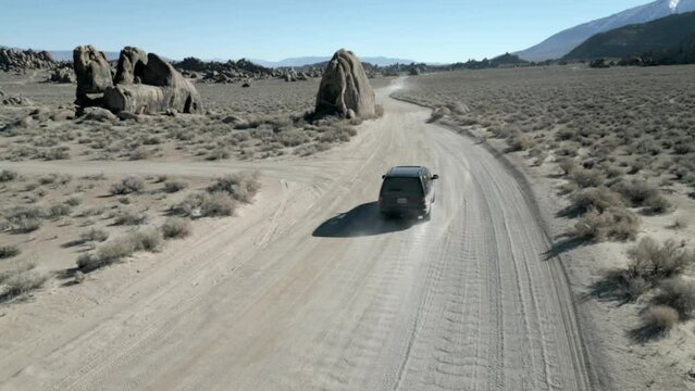 Desert chasing black SUV with drone through rocks around Alabama Hills