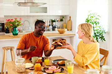 Multiracial couple enjoying breakfast together at home