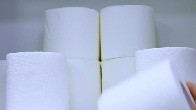 Female hand taking a toilet paper roll from a shelf close up