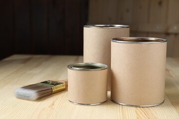 Cans with different wood stains and brush on wooden surface, space for text