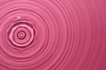 Rippled surface of clear water on bright pink background, top view