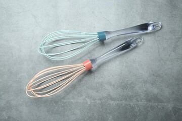 Two whisks on gray table, top view