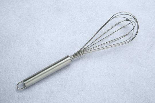 Metal whisk on gray table, top view