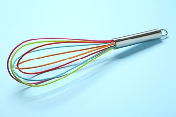 One whisk on light blue background, closeup
