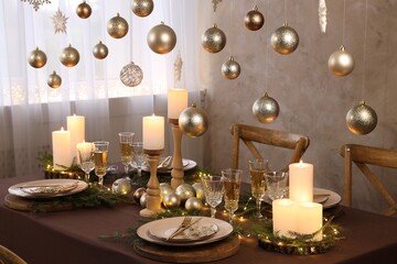 Christmas table setting with burning candles and festive decor