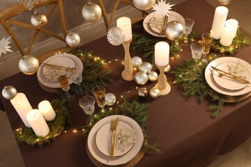 Christmas table setting with burning candles and festive decor