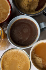 Upside viev of several coffees. Some of them have milk, some are black, hot, iced, on a white tableccloth