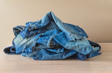 Heap of old torn jeans on the wooden background