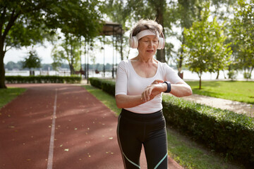 Senior woman looking at wristwatch running in park
