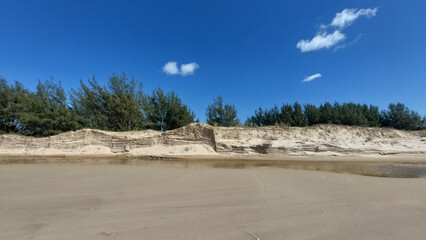 Fototapeta na wymiar Beach with sand dunes ,river and trees under blue sky with clouds