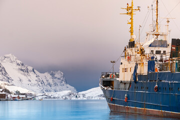 Fishing boat in harbor of Norther Norway. Red rorbu, fishing trawler and cold sea water in sunny...