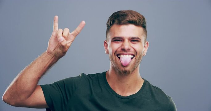 Rock, hand or face of happy man in studio on grey background for freedom, energy or emoji. Smile, crazy or portrait of a cool person isolated for devil horns gesture, punk sign or edgy attitude alone