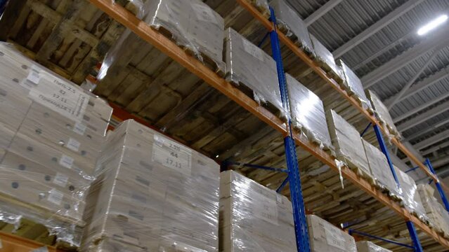 Packaged goods stored in warehouse. Serial numbered goods ready for shipment stand on wooden shelves in storehouse in industrial park