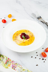 Ginger pumpkin soup with dumplings and berries. White background side view