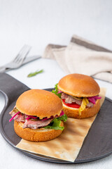 hot burgers with lettuce and vegetables on a wooden board side view