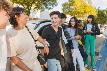 Obraz premium Cheerful multiethnic friends standing and leaning on cars on street