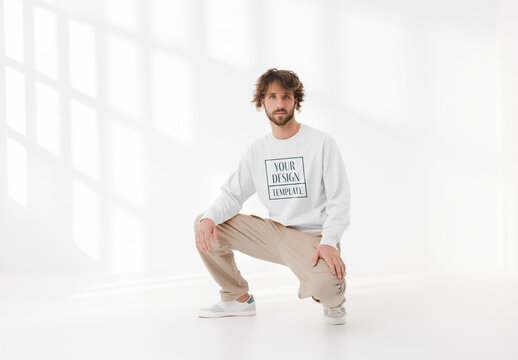 Mockup of man wearing customizable sweatshirt crouching in studio
