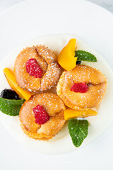 muffins with peach, raspberry, black berry and mint covered with powdered sugar, top view