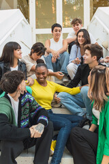 Group of happy diverse friends sitting on stairs of glass door entrance in daylight
