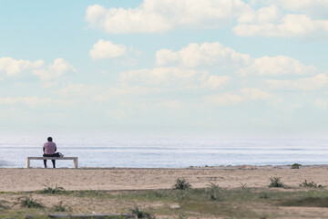 Fototapeta na wymiar A Tranquil Moment: A Person Sitting on a Bench, Enjoying the Serene Beachscape