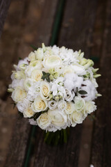 Wedding bouquet with white flowers on a wooden stairs. Bouquet with ranunculus, lisianthus, freesia and cotton flowers.