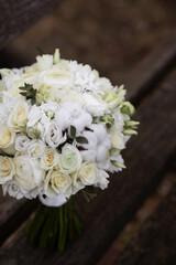 Wedding bouquet with white flowers on a wooden stairs. Bouquet with ranunculus, lisianthus, freesia and cotton flowers.
