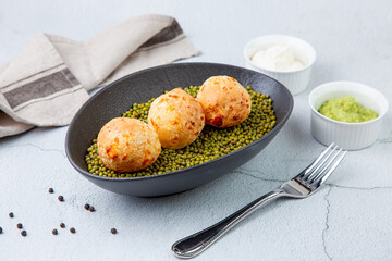 cooked meatballs on peas in an oblong bowl side view