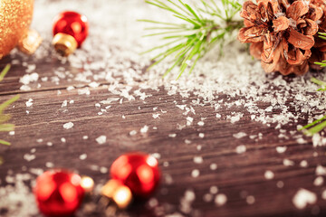 Wooden table with pine branches, snow and Christmas ornaments with copy space