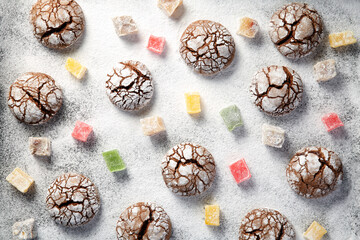 Top down view of many scattered crackled cocoa cookies and colorful turkish delight slices over snow like powdered sugar background. Traditional Christmas treats viewed from above