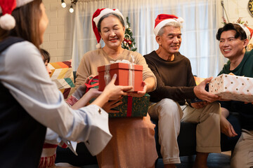 Asian family give gift box or present to grandmother and grandfather in celebrating Christmas at home
