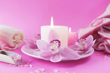 Fototapeta na wymiar Fresh pink orchid flowers, burning candles, sea salt, on a bright pink background, spa concept, relaxation atmosphere, body care 
