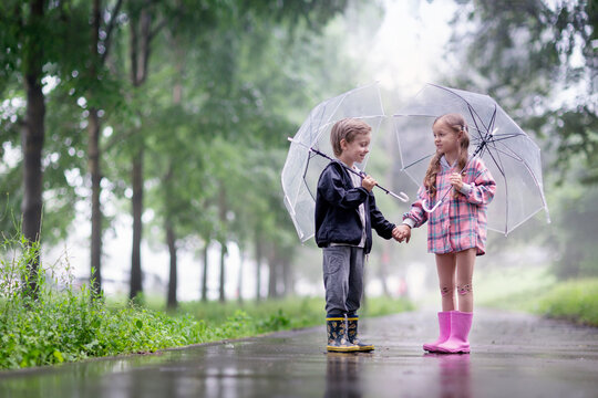 a little boy and a girl are talking outside under umbrellas after the rain