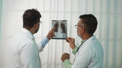 two Indian Doctors discussing from x-ray or medical report at hospital - concept of healthcare professionals, specialist advice and collaboration.
