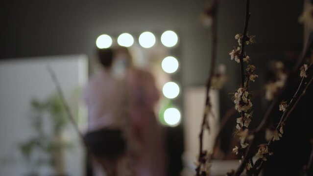 Defocused and blurred photo of a cozy workplace of a make-up artist. Applying makeup on the face of a girl. 