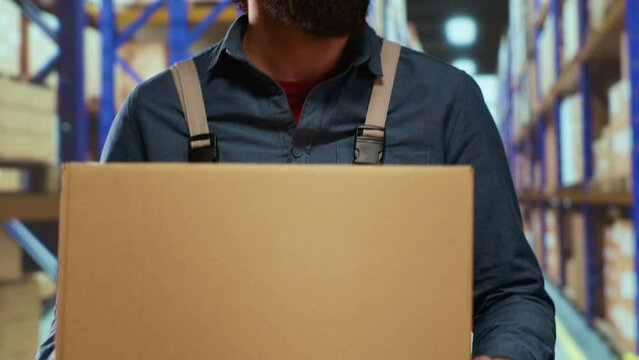Packaging advisor having merchandise boxes in hands, trying to organize stock and parcels based on delivery time or labels. Warehouse employee preparing to place packages on industrial racks.