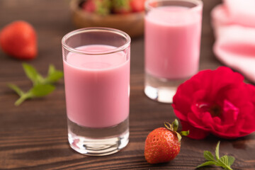 Sweet strawberry liqueur in glass on a brown wooden background. side view, selective focus