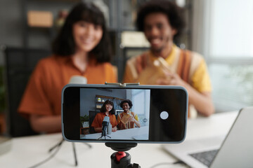 Screen of smartphone with two young intercultural bloggers showing goods