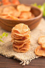 Slices of dehydrated salted meat chips on brown wooden, side view, selective focus