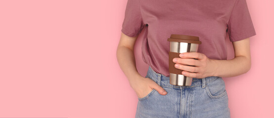 Banner with woman hold in hands reusable coffee cup in front of pink background. Take away drinks concept with copy space. Selective focus.