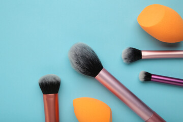 Makeup buffer brush and beauty makeup sponges on blue background. Beauty and makeup concept - obrazy, fototapety, plakaty