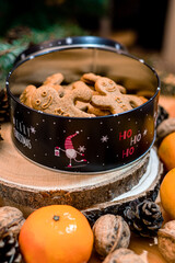 Christmas box with gingerbread men, complemented by natural decorations walnuts, pine cones, oranges evoking warm holiday ambiance, rustic charm, one gingerbread man holding another one's hand.