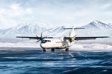 White passenger turboprop aircraft on the winter airport apron on the background of high scenic mountains