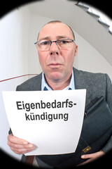 Blick durch den Türspion:Vermieter vor der Wohnungstüre mit Kündigungsschreiben wegen Eigenbedarf