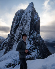 Hiker climbing snowy mountain hike up Segla in Senja, Norway.  A man walking up snowcapped...