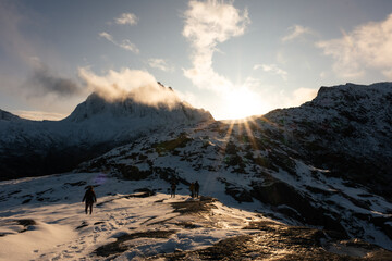 Hiker climbs over mountains in Norway as the sun shines over the peaks at sunset