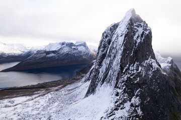 Aerial drone photo of snowy mountain hike up Segla in Senja, Norway.  Snowcapped mountains in the Arctic Circle of Northern Norway.  Famous hike on Senja island.  Shot in October. - obrazy, fototapety, plakaty
