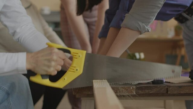 Cropped shot of unrecognizable female activists of feminist movement using saw while making protest flag together before going on strike to fight for womens rights and equality