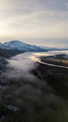 Beautiful aerial of river in Northern Norway with clouds, fog, and mountains.  Winding river shot on a drone.