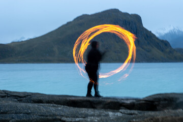 Fire dancer performing at Haukland beach in Northern Norway located in the Arctic Circle.  This...