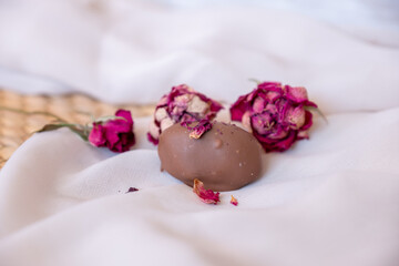 Chocolate pieces with flowers and roses on pink and white background also with mock up space